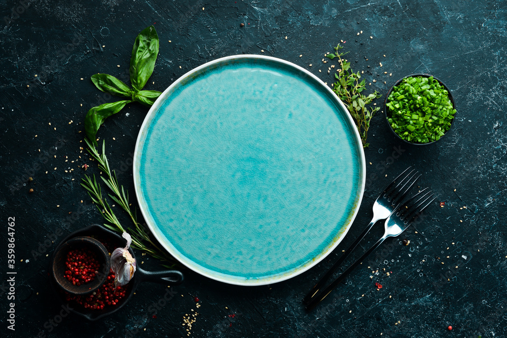 Wall mural blue plate with vegetables and spices on a black stone background. top view. rustic style.