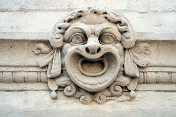 Masque ancien sculpté sur une façade en pierre