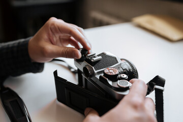 Male hands reloading film retro camera on a white table