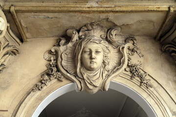Tête de femme sculptée en pierre sur une façade ancienne. Paris.