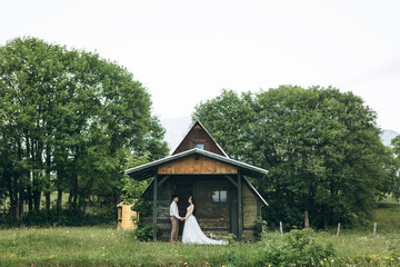 The bride and groom are standing next to the house. Rural or rustic scene