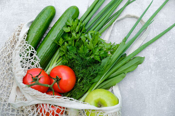 Reusable grocery net bag with fresh vegetables and fruits on stone background. Top view. Healthy organic food delivery, shopping, buying