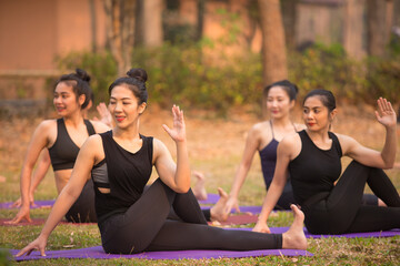 Asian Beautiful Women Group Doing yoga by the lake in the morning with warm sunshine