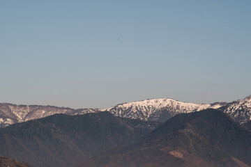 View of the foothills of the Caucasus. High peaks are covered with snow. Mountains against the blue sky. Day. Sunny. Georgia.