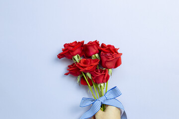 Hand of holding Red rose flowers on purple background. Floral composition, flat lay, top view, copy space