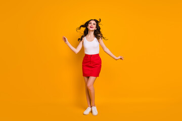 Fototapeta na wymiar Full length photo of pretty lady hairdo flight satisfied look enjoy warm summer breeze wear white casual tank-top red short skirt shoes isolated yellow bright color background