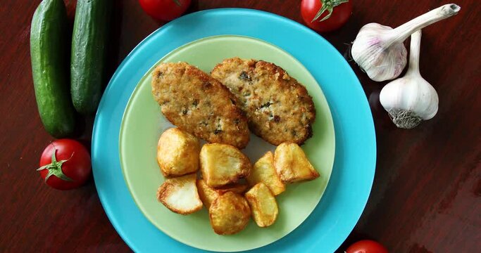 Fried potatoes with cutlet, tomato, cucumber, garlic close up