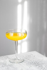 Simple Alcoholic cocktail on white background with sun shadow in the wall.
