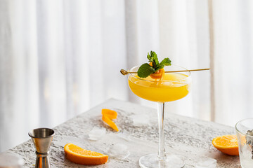 Close up of Alcoholic orange cocktail with stylish garnish on white concrete background.  Copy space