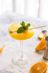 Close up of Alcoholic mimosa cocktail with stylish garnish on white concrete background.  Copy space