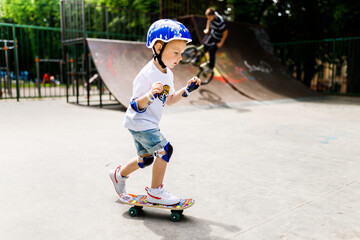 Obraz premium Boy with a skate in a skate park. The boy learns to skate, in full protection.