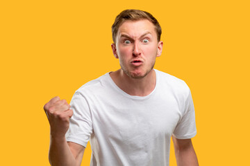 Obraz premium Angry man portrait. Warning gesture. Annoyed guy threatening with fist isolated on orange background.