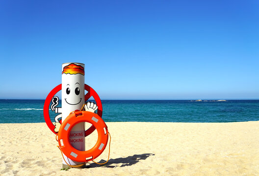 No smoking sign with lifebuoy on a white sand beach with emerald water on a sunny day. Sea landscape.