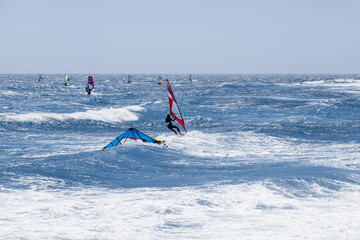 Group of windsurfers practicing in the ocean with colorful sails