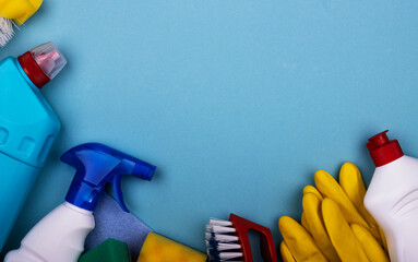 cleaning products in plastic bottles, rubber gloves with a sponge on a blue background, top view