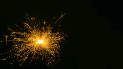 Happy New Year, sparkling burning sparkler or salute on a black background. Holiday concept, background, copy space