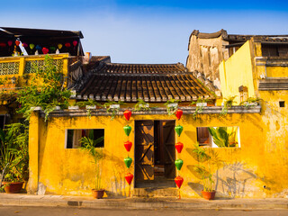 Green and red lanterns hanging outside of an old yellow house in Hoi An ancient town, UNESCO world...