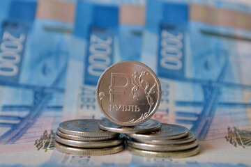 Russian metal 1 ruble on a stack of coins against the background of the banknote 2000 rubles