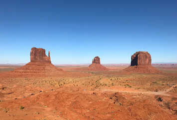 Fototapeta na wymiar Amazing view of Monument Valley with red desert and blue sky and clouds in the morning. Monument Valley in Arizona with West Mitten Butte, East Mitten Butte, and Merrick Butte. 