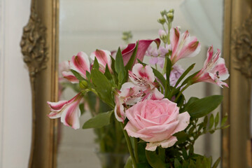 A bouquet of different pink  flowers in front of a mirror