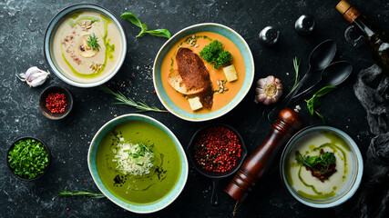 Set of colored soups in bowls on a black stone background. Healthy food. Top view. Rustic style.