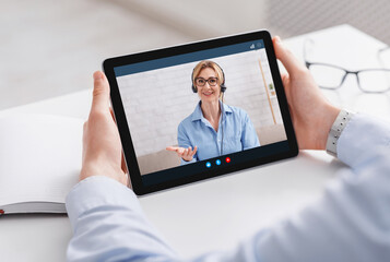 Online work and communication with consultant. Man holding tablet with video call of woman
