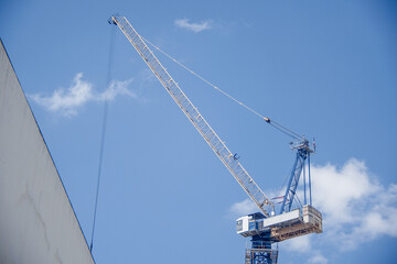 Fototapeta na wymiar Very high construction crane with blue sky in the background