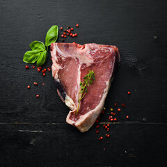 Raw aged T-bone steak on a black stone background. Top view. Rustic style.
