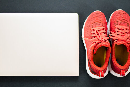 Gym shoes and laptop - concept for performing sports at home online (e.g. home workout in times of corona)