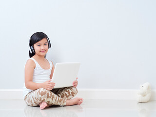 Little girl with laptop sitting on floor.