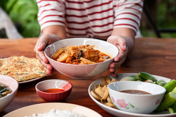 Thai local homemade food red curry with chicken in ceramic bowl at dinner table
