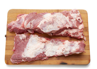 raw strip of pork meat on ribs with layers of fat on a wooden cutting board