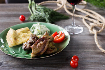 fried meat on a green plate is on the table. There is a glass of wine next to it