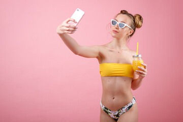 girl in a swimsuit and glasses with juice takes a selfie. summer mood