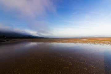 Coastal view from Red Wharf Bay of the early morning mist dispersing overhead, Isle of Anglesey, North Wales