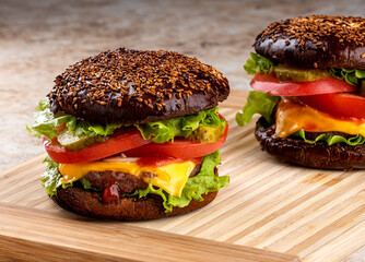 classic american homemade burger on the kitchen board. Bun with sesame seeds, pickled cucumbers, cheddar cheese, tomatoes, onions, meat cutlet.