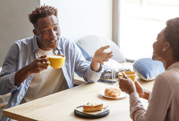 Beautiful romantic couple talking with each other and enjoying coffee at cafe