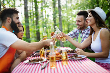 Group of happy friends eating and toasting at garden barbecue