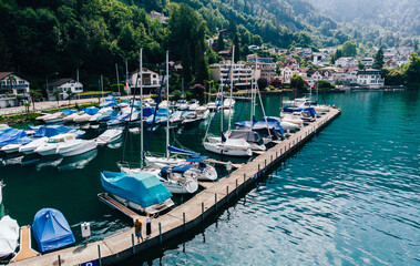 Fototapeta na wymiar Aerial view of private motor boats moored in a small sea port surrounded by nature piedmont. Colorful fisherman's boats in dock harbour