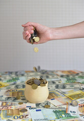 coins are falling in the cup. coins pour out of a female hand