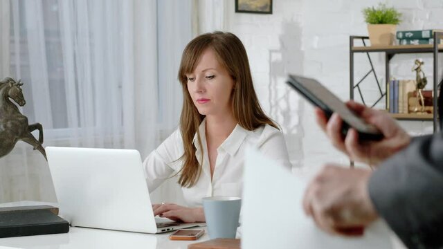 Young business woman working at desk with laptop computer in home office. Slow zoom in.