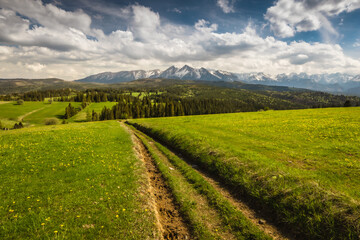 Spring in the Tatra Mountains. Green fields against the backdrop of snowy peaks. Landscape photo from Lesser Poland.