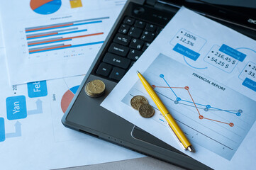 Selective focus of laptop, coins, papers, glasses, pen and calculator on table