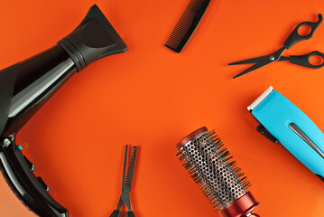 Hairdryer, comb, scissors and clipper isolated on a orange background. Copy space and place for text. Layout for design. Mockup