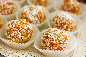 Healthy raw energy balls. Candy vegan balls of dates, coconut pulp, carrots in a wooden bowl are laid out in the shape of a pyramid. Top view, concept of useful home-made candies without sugar