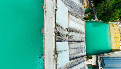 Aerial top view of dam as barrier that stops flow of turquoise water. Construction for generate...