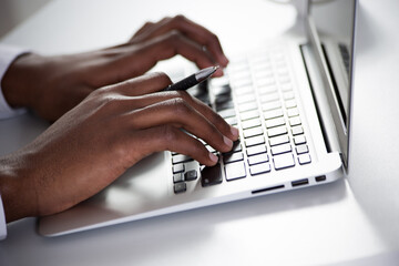 Fototapeta na wymiar Close-up of hands of african-american businessman typing on a laptop.