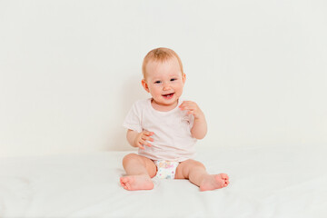 Baby in T-shirt and diaper laughs on white background