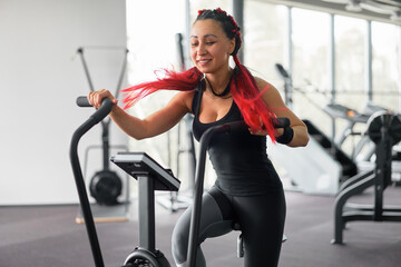 Woman exercise bike gym cycling training fitness. Fitness male using air bike cardio workout.