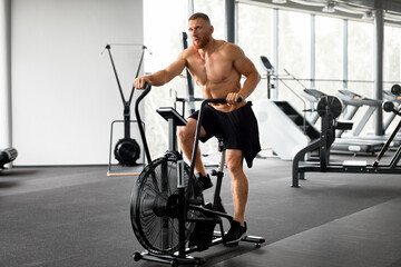 Fototapeta na wymiar Man exercise bike gym cycling training fitness. Fitness male using air bike cardio workout.